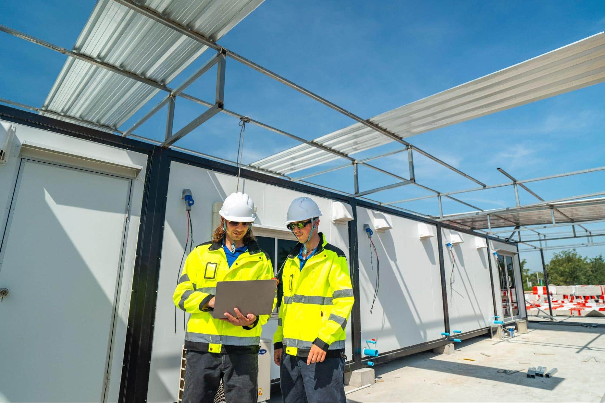 inżynierowie na placu budowy stojący przy kontenerach biurowych